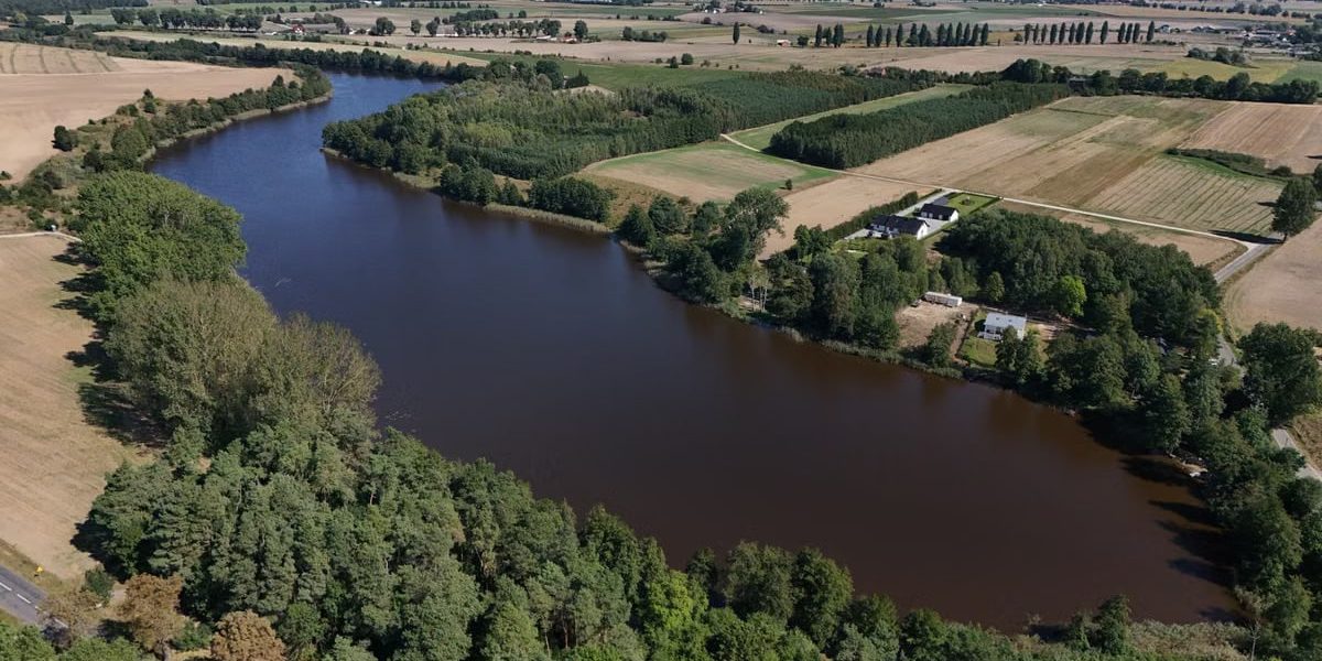 A stunning aerial view of a rural river landscape with lush greenery and open fields.