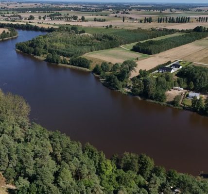 A stunning aerial view of a rural river landscape with lush greenery and open fields.
