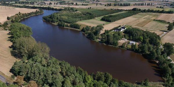 A stunning aerial view of a rural river landscape with lush greenery and open fields.